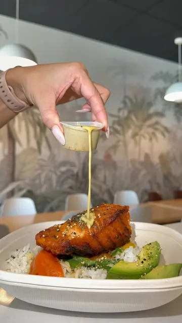 A hand pouring sauce over a savory plated dish